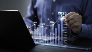 Businessman Analyzes The Graph Of Trend Market Growth In 2025 And Plans Business Growth And Profit Increase In The Year 2025. Plan Finances Of The Business